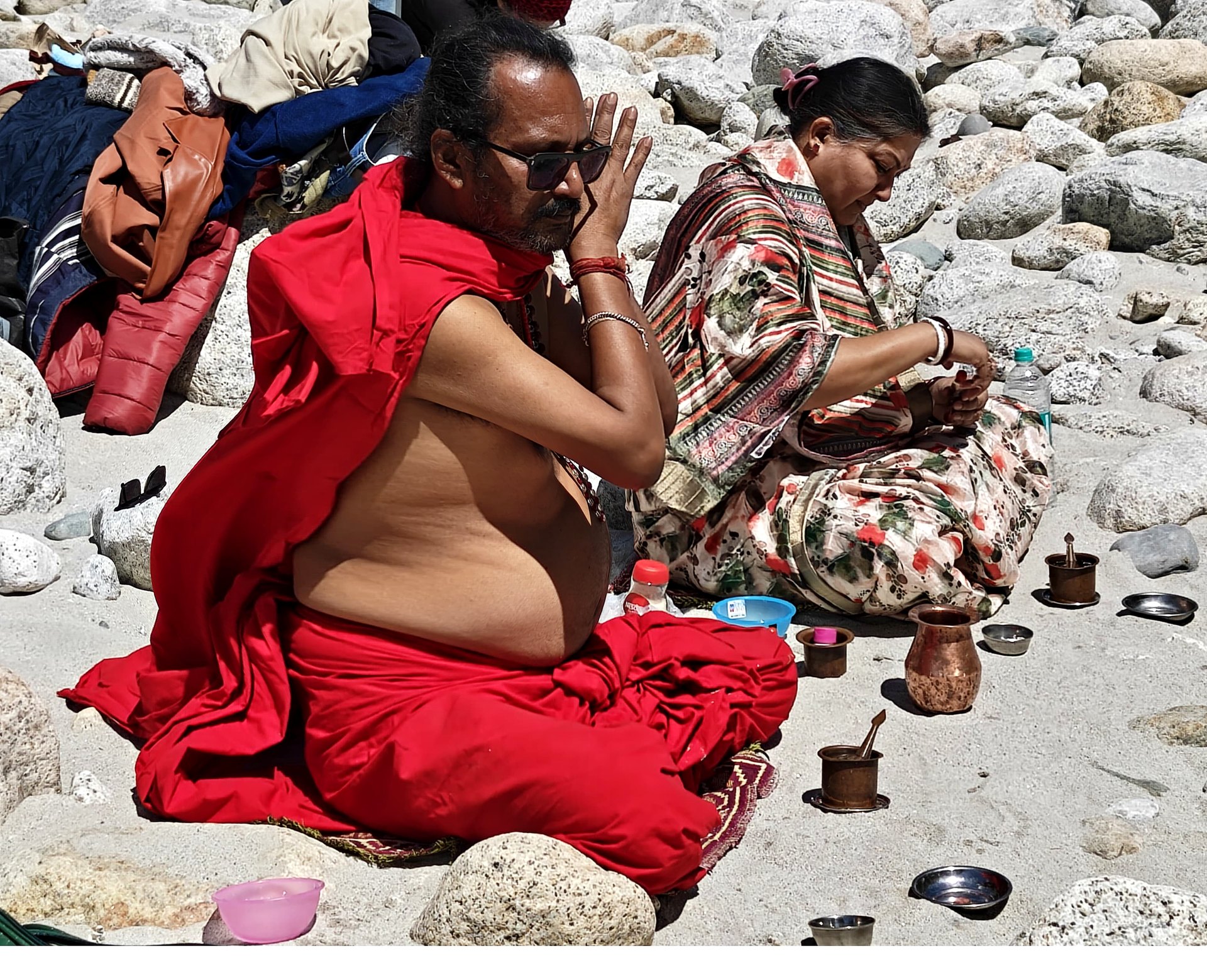 Sri Meenananda Tirthanath in pranam at a Himalayan riverbank, with Guruma seated nearby.