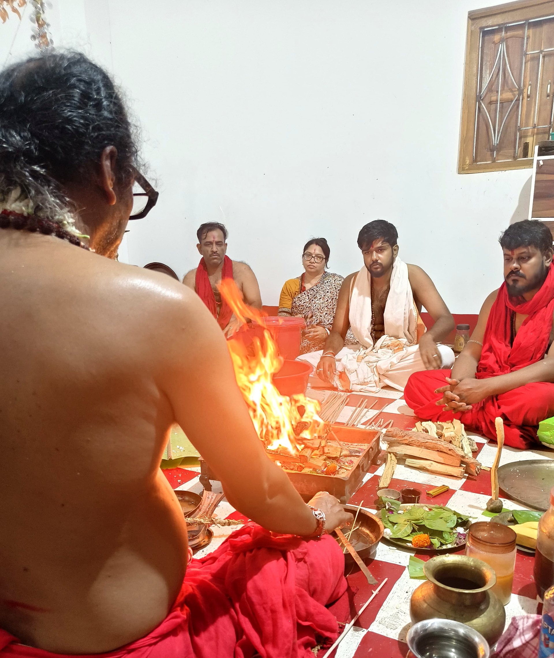 Homa fire during puja, with devotees seated around the sacred fire.