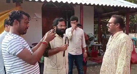 Sri Meenananda Tirthanath speaking with reporters in a courtyard.